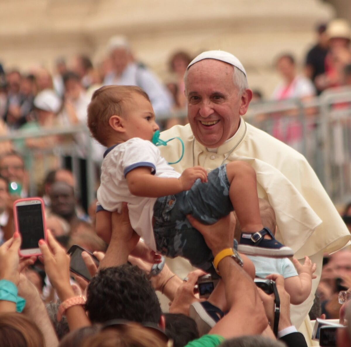 Pope Francis smiling and addressing a gathering with compassion and humility.