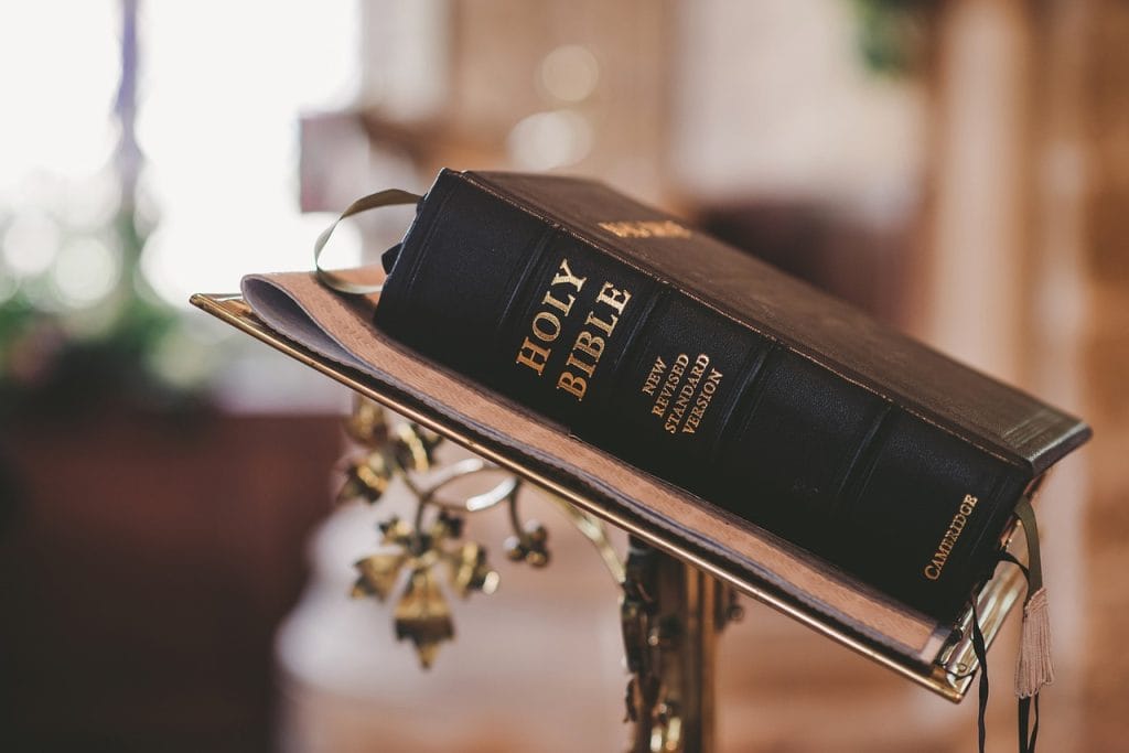 Open Bible on a wooden table with soft light, symbolizing faith, prayer, and the Word of God.